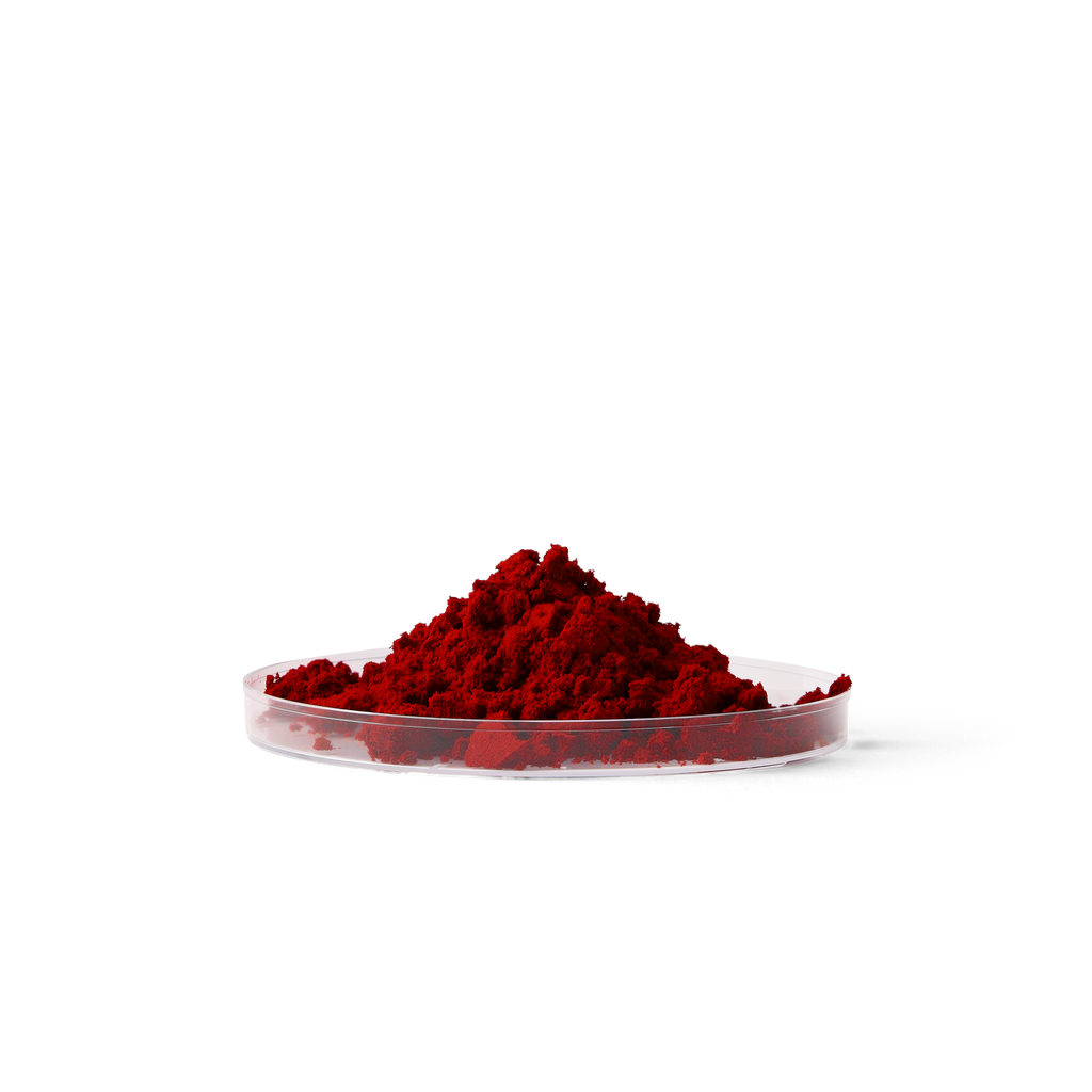 A small mound of bright red astaxanthin powder piled in a shallow clear dish against a plain white background.