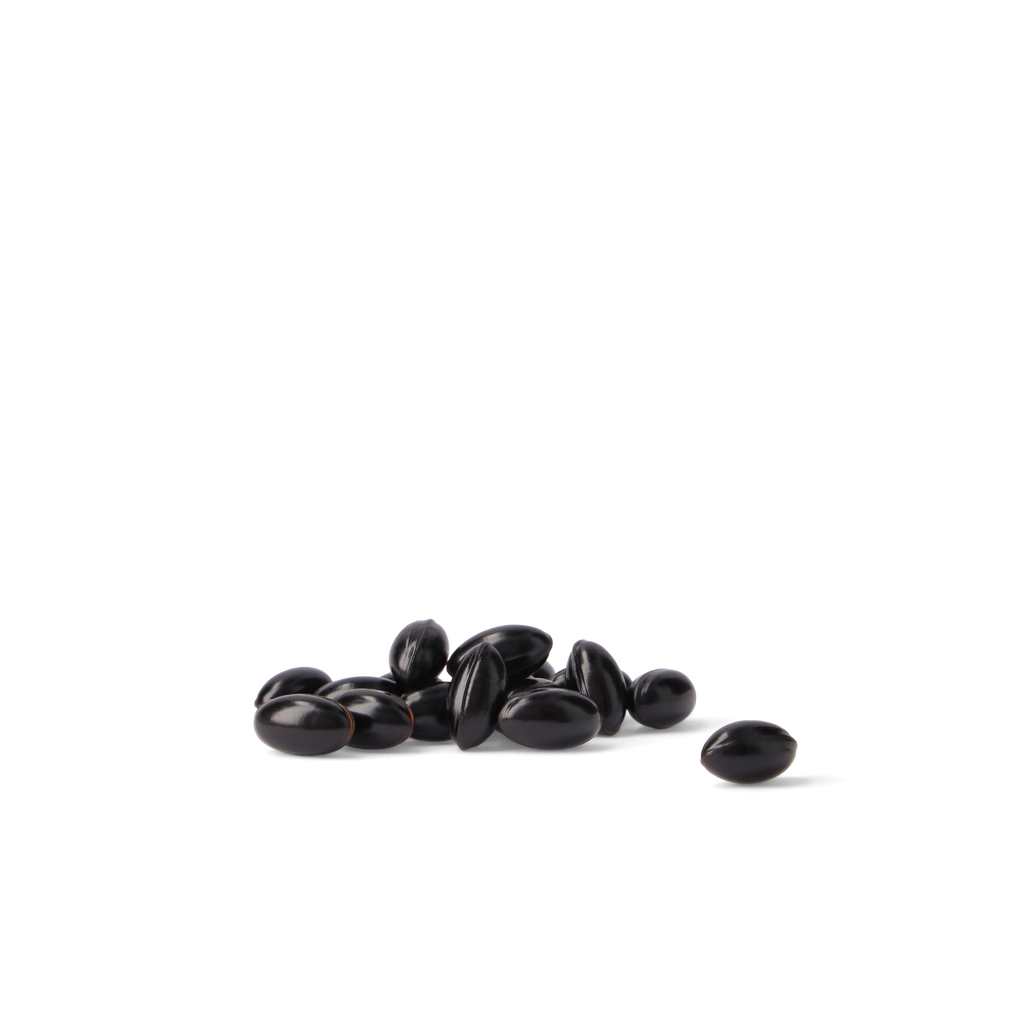 A small pile of glossy black beans with one bean placed to the right, photographed on a clean white background.