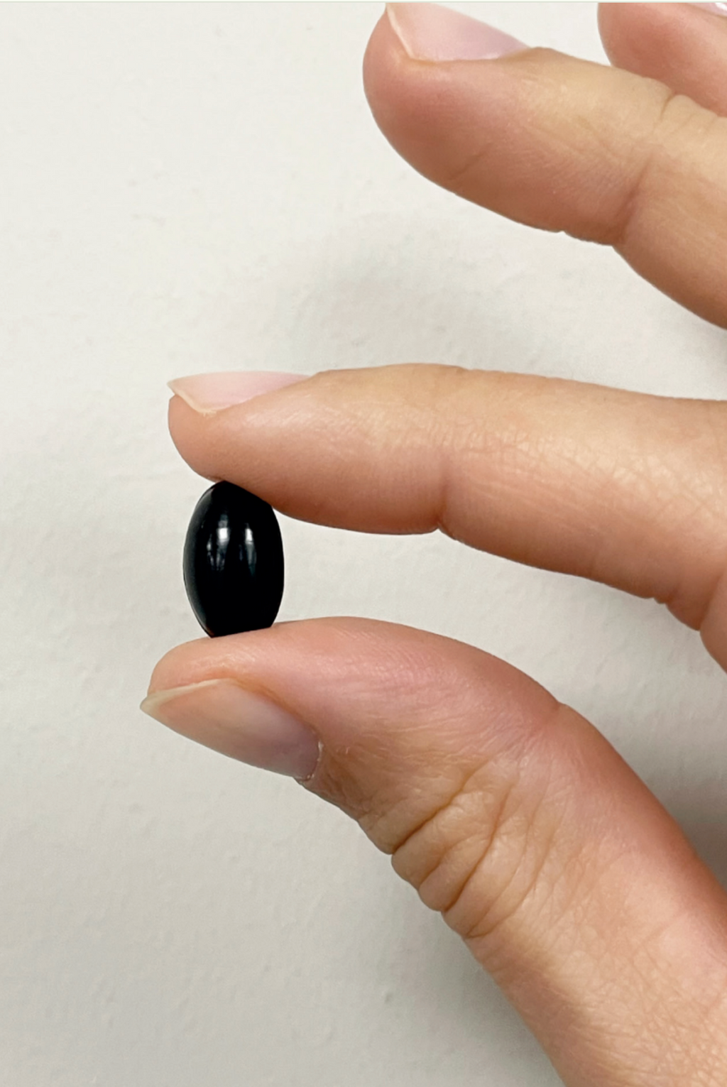 axacaps, natural astaxanthin in softgel vegan between finger