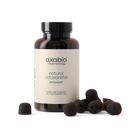 A bottle of axabio natural astaxanthin antioxidant supplement with several dark red astaxanthin capsules scattered in front, set against a solid white background.