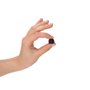 A hand with a French manicure holds a tiny black, rounded object between her fingers against a solid white background.