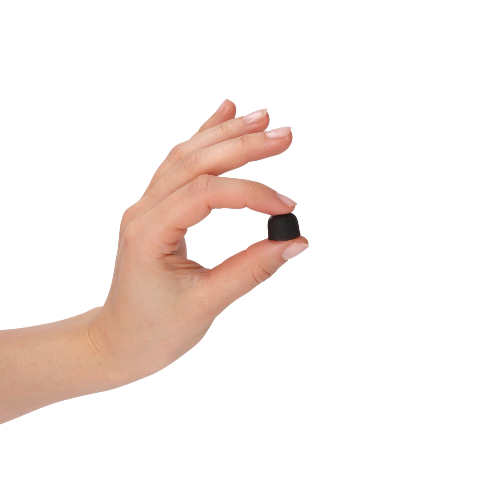 A hand with a French manicure holds a tiny black, rounded object between her fingers against a solid white background.