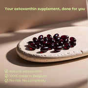 Red astaxanthin supplement vegan softgel capsules on a stone board with promotional text.